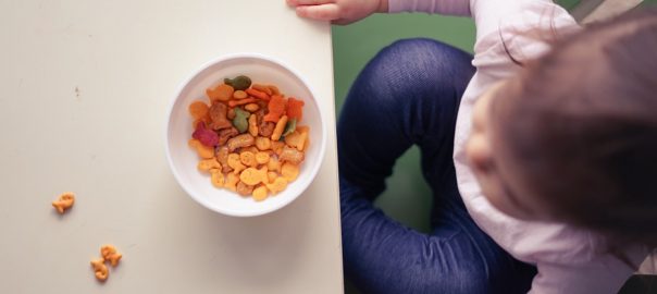 toddler sitting in front of bowl on top of table